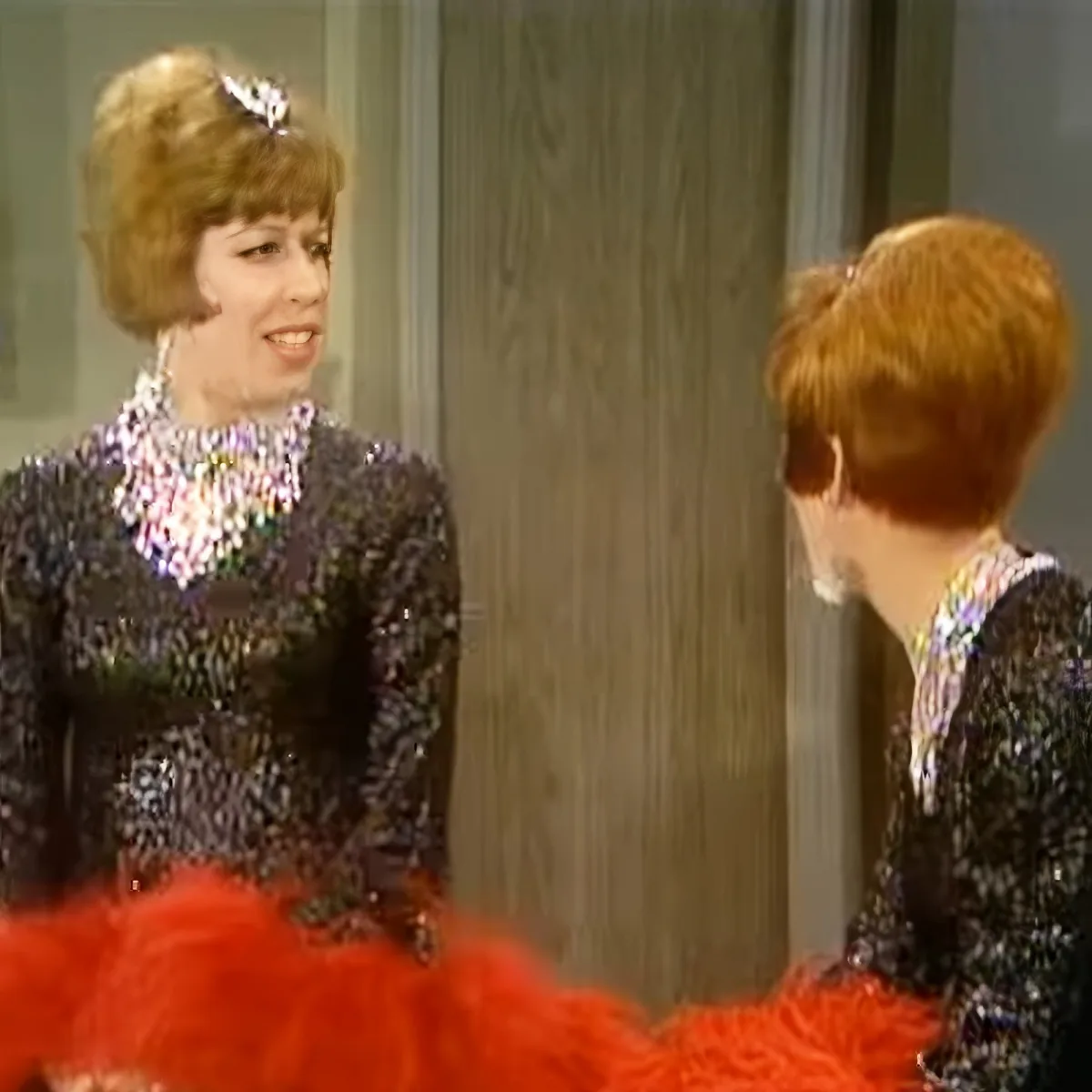 A woman in a sparkly black dress and red tutu is smiling at another woman with red hair.