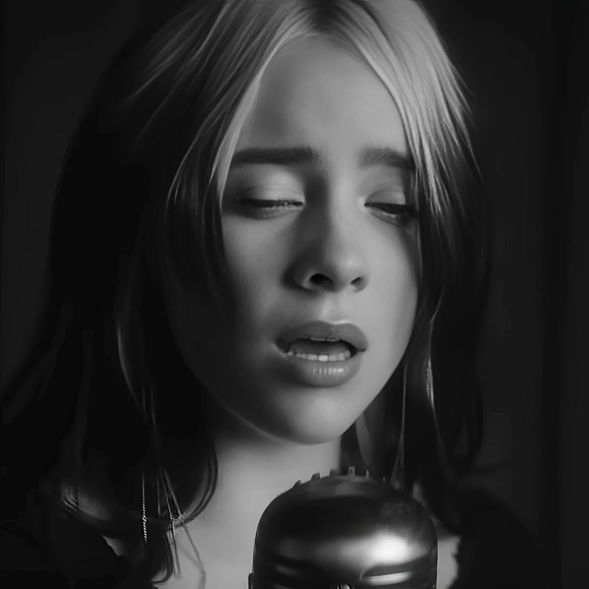 A person with long hair and closed eyes is singing into a microphone.