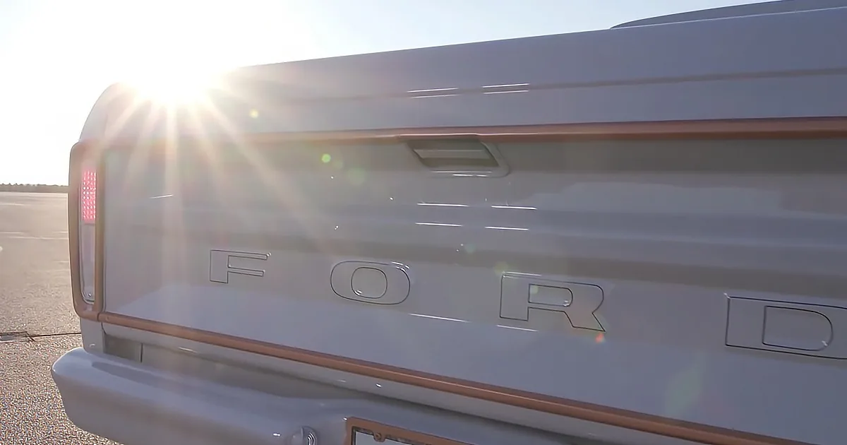 A Ford vehicle's rear is shown with the sun shining brightly behind it, creating lens flares.