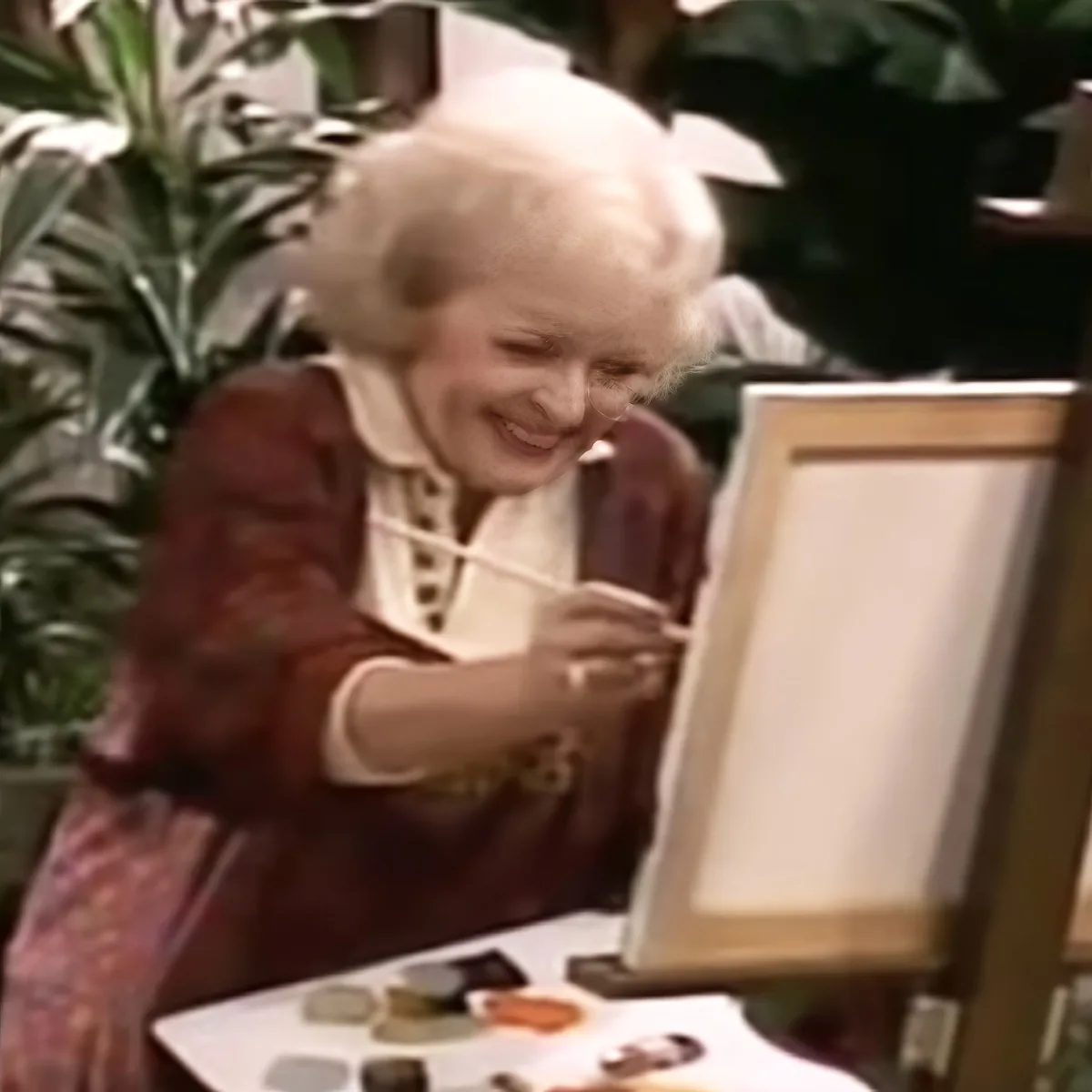A person in a historical costume is painting on a canvas with a paintbrush.