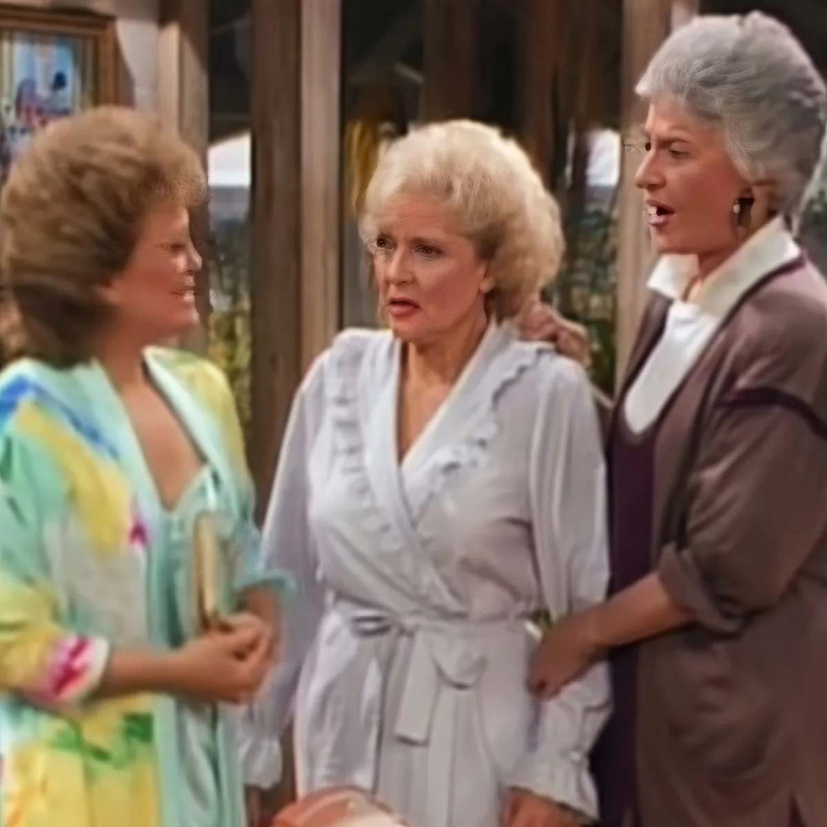 Three women in a room, one in a robe, another in a suit, and the third in a colorful robe, seemingly engaged in a...