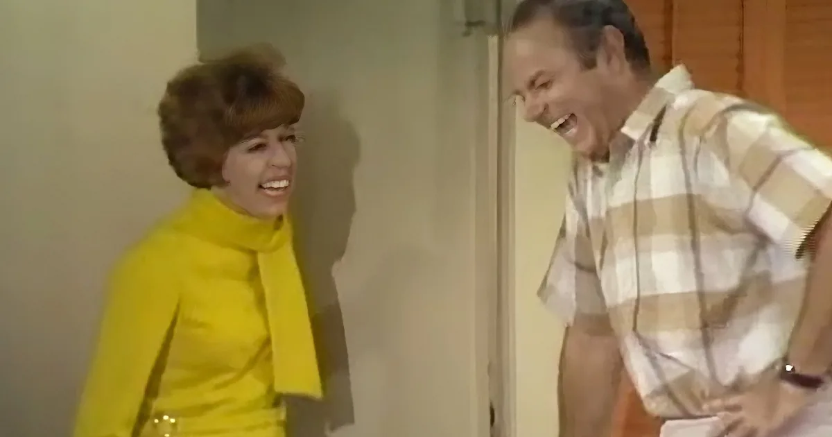 A woman in a yellow outfit and a man in a plaid shirt are laughing together.