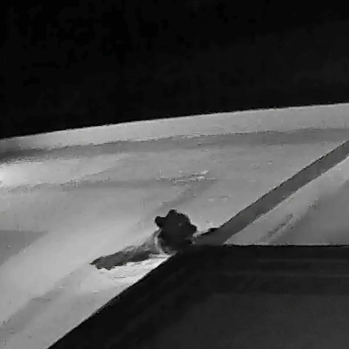 A person wearing a hat is climbing up a snowy slope at night.
