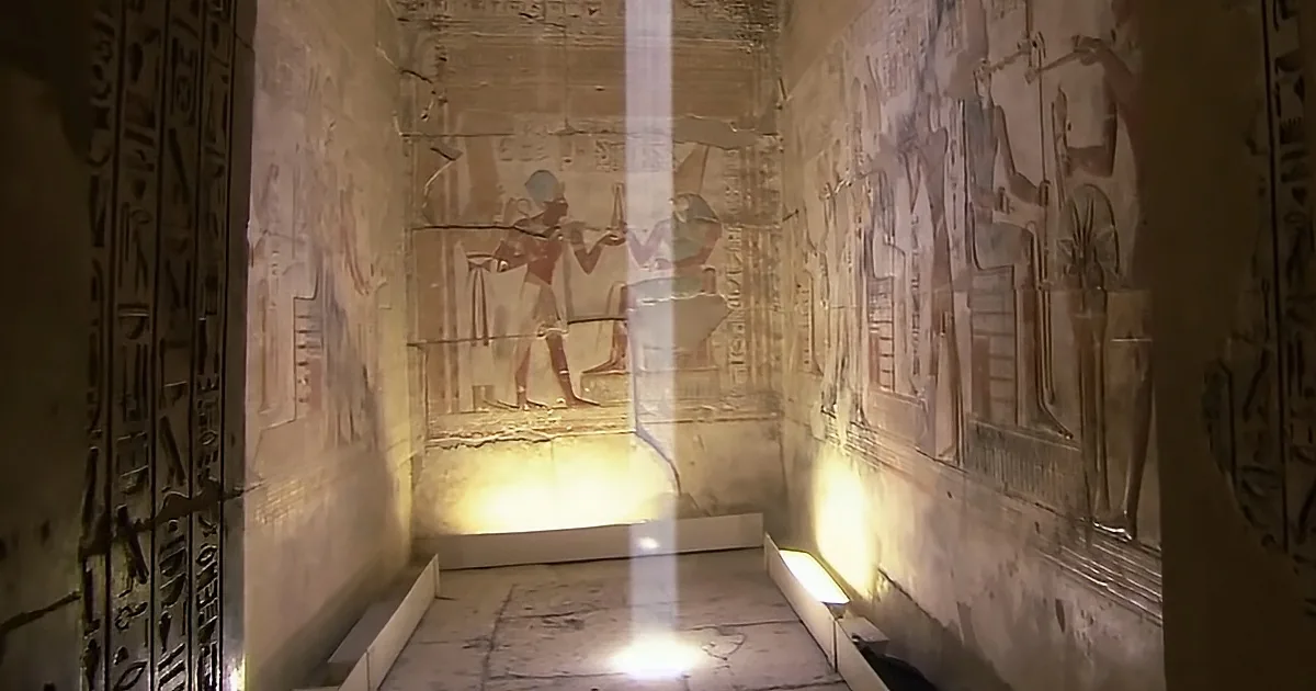 Ancient Egyptian temple with hieroglyphics and figures on walls, illuminated by light.