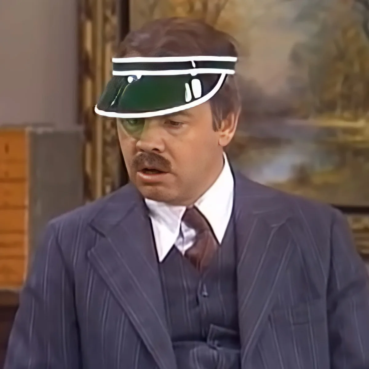 A man in a pinstripe suit and green visor hat is looking to the side with a surprised expression.