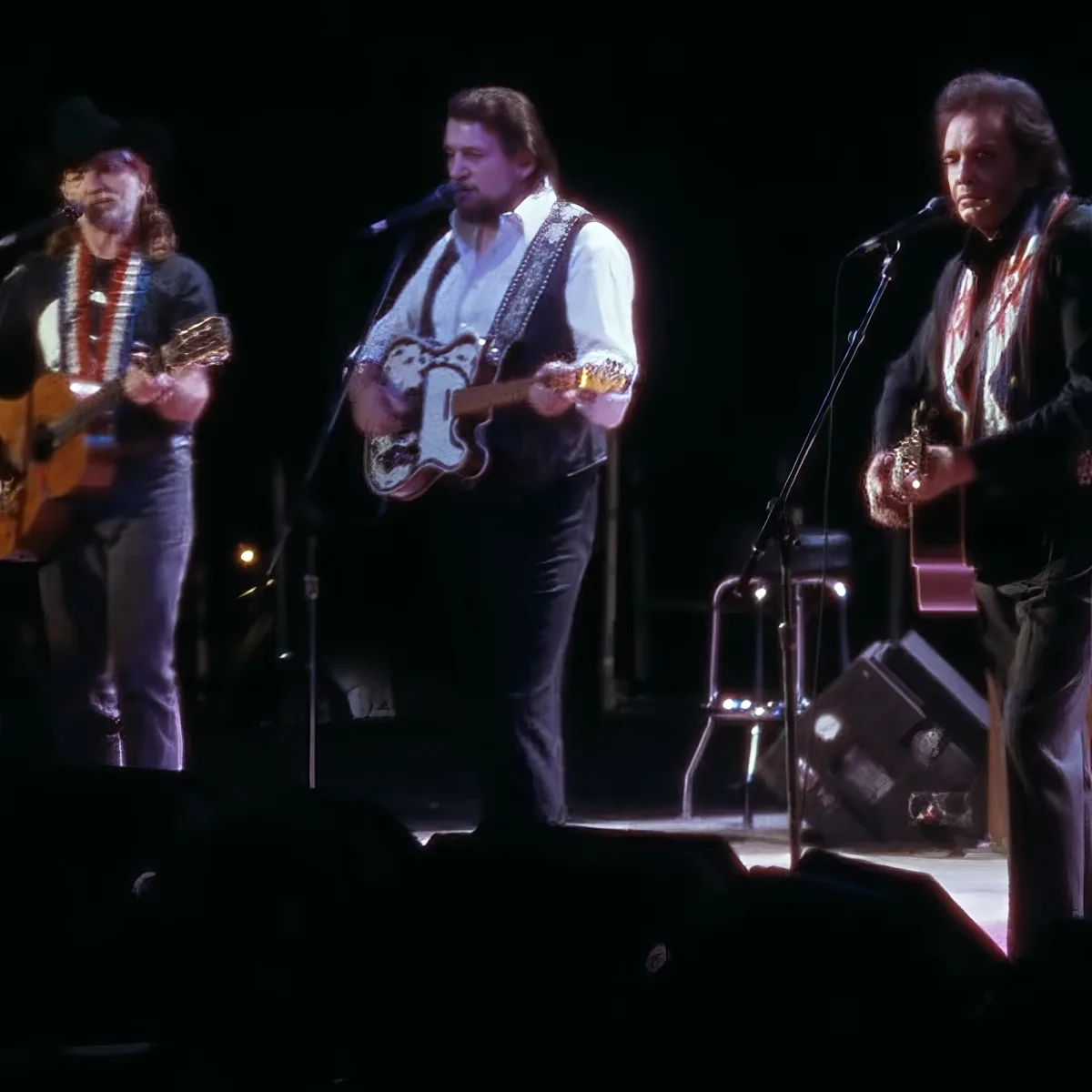 Three musicians perform on stage, each playing guitar and singing into microphones.