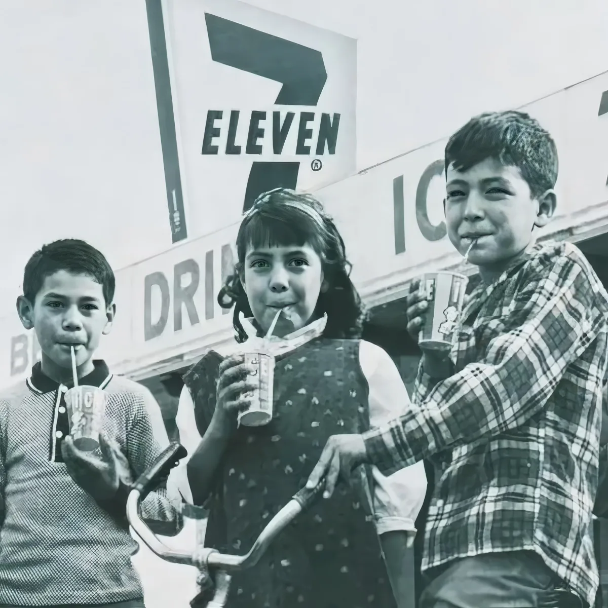Three children holding drinks, smiling, with a 7-Eleven sign in the background.