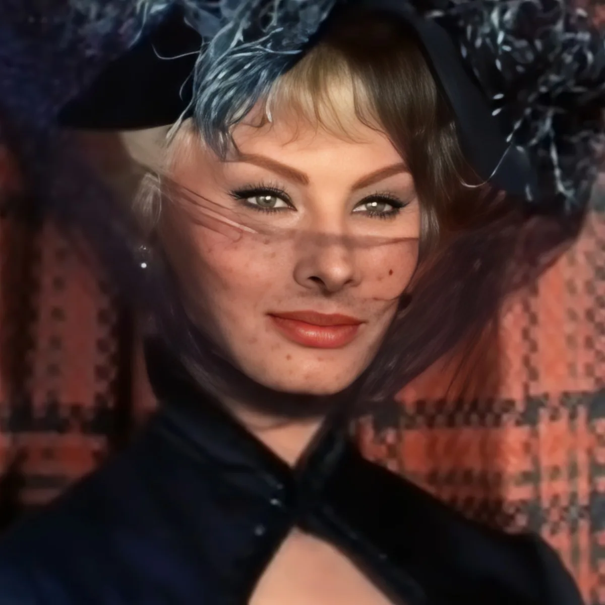 A person with blonde hair, wearing a black outfit and a patterned scarf, is seen in a close-up shot.