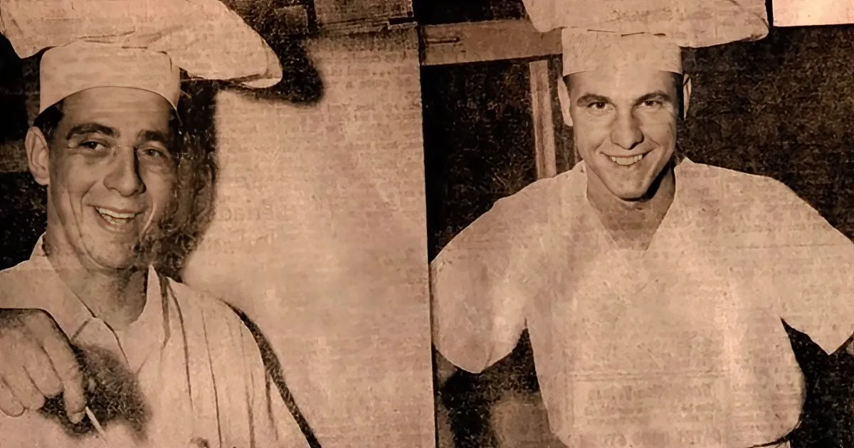 A man in a chef's uniform and hat is smiling, holding a utensil, in a sepia-toned image.