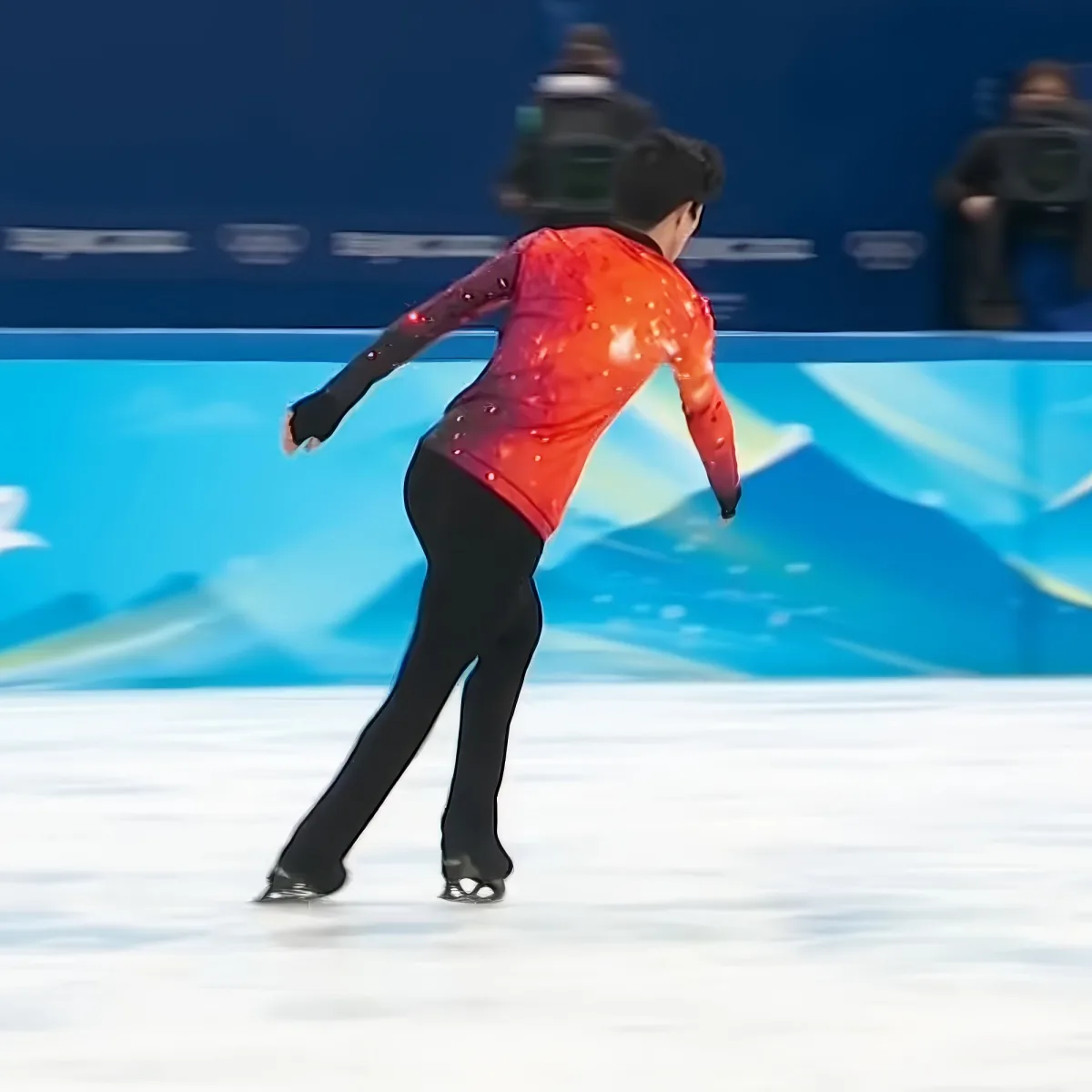 A figure skater in a red outfit glides gracefully on the ice.