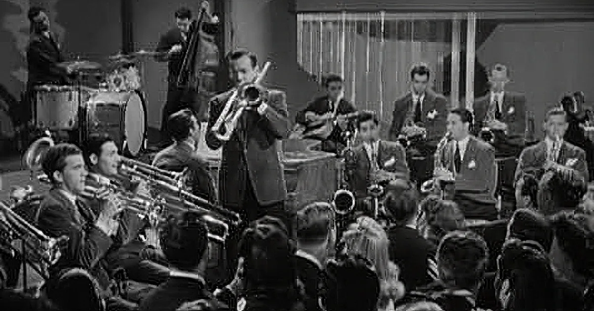 A jazz band performs on stage with a trumpet player in the foreground and musicians in suits playing various instruments.