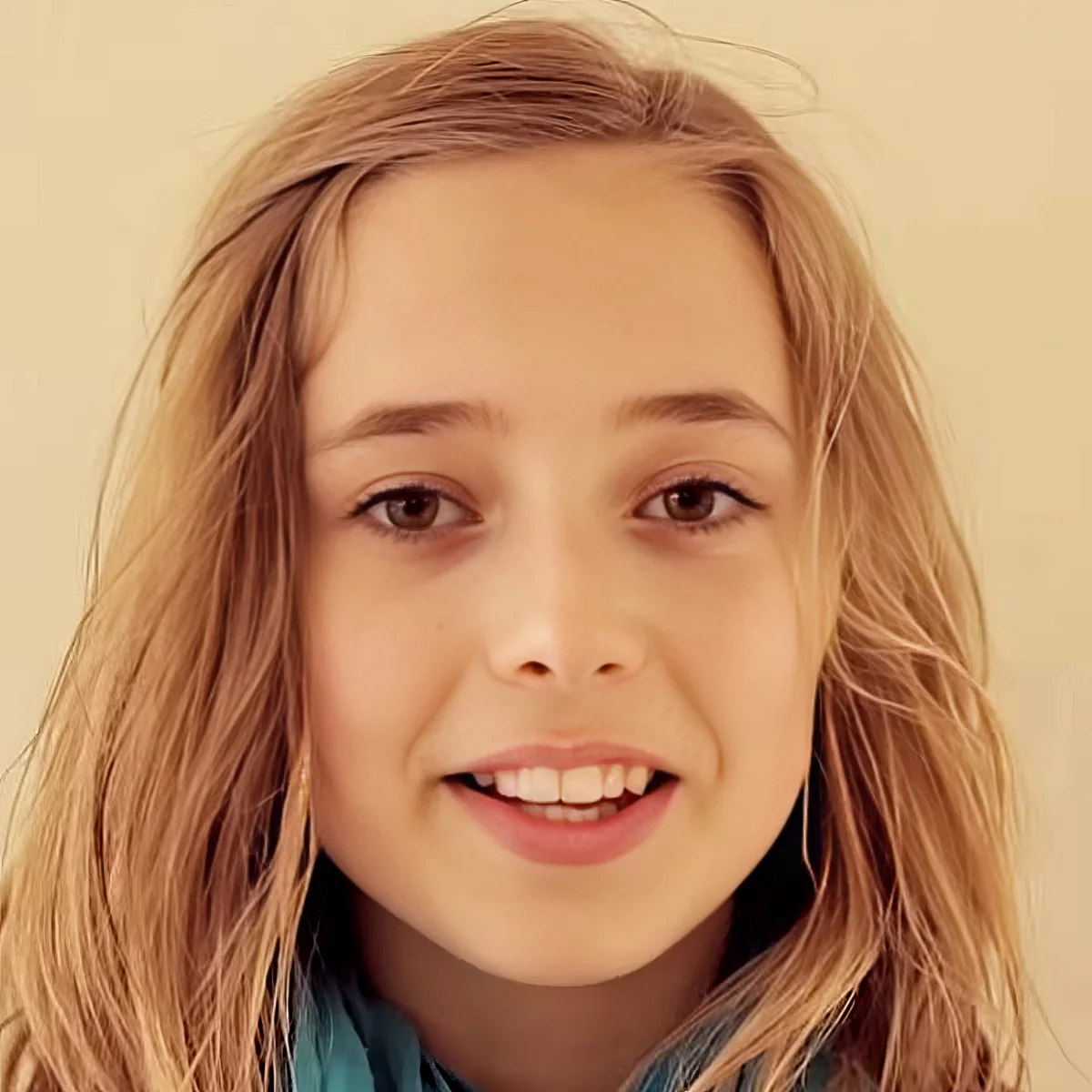 A young girl with long, light brown hair and a bright smile is the main subject of the image.