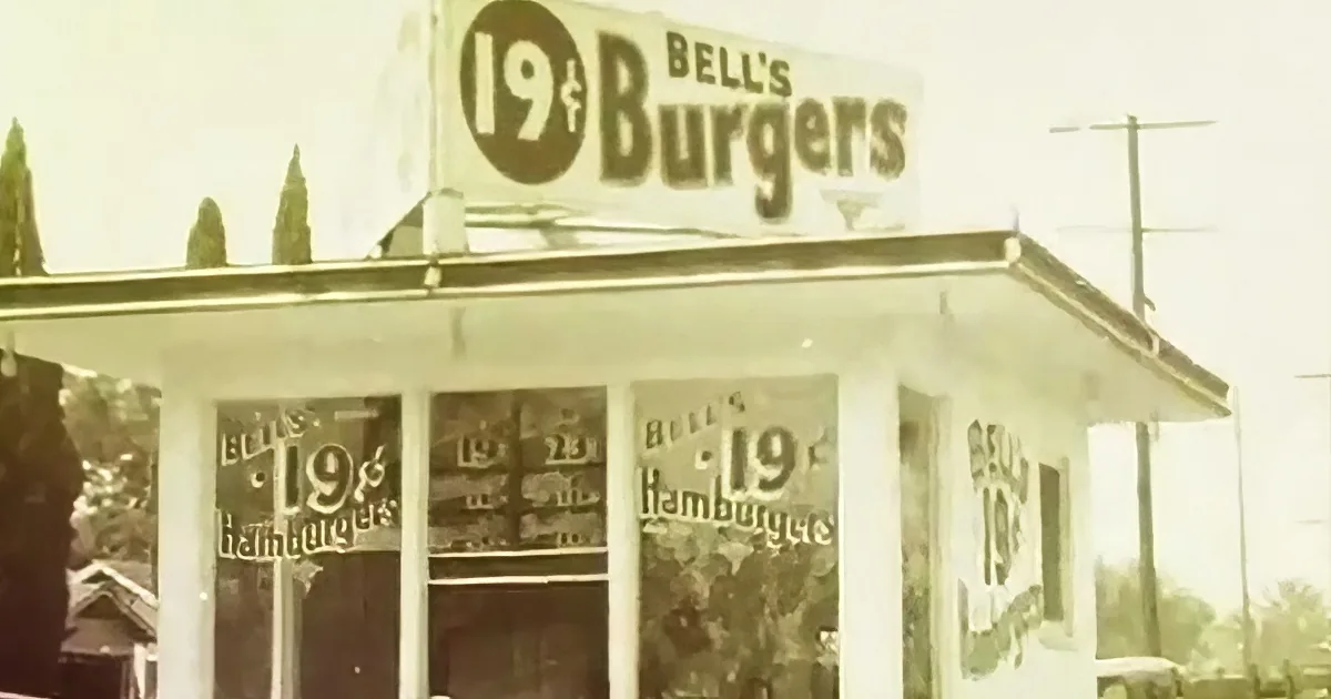 Bell's 19¢ Burgers sign atop a white building with multiple windows.