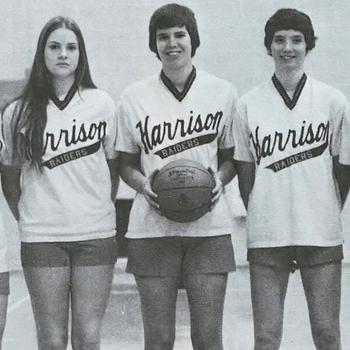 Three individuals in "Harrison Raiders" shirts stand together, one holding a basketball.
