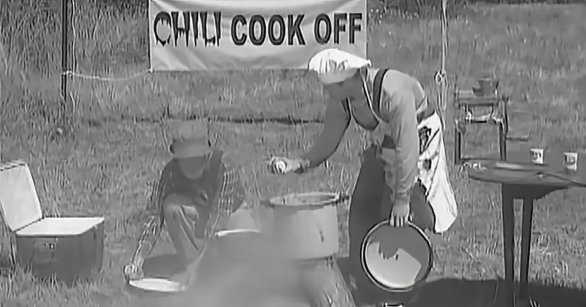 A person in a white hat pours from a can into a large pot at a chili cook-off event.