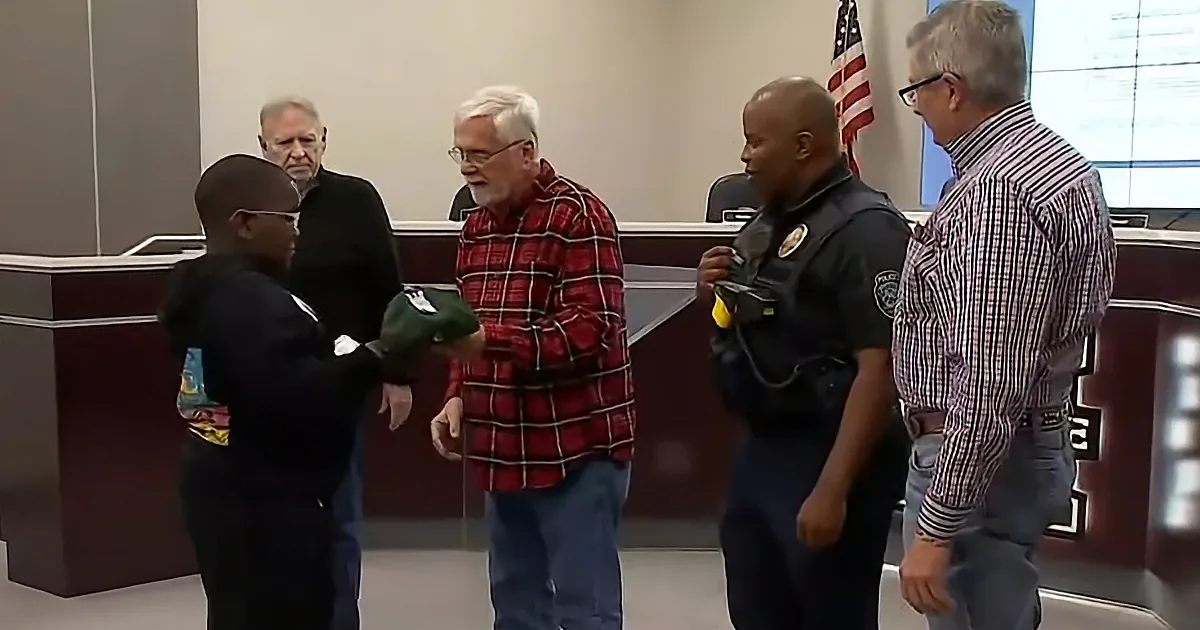 A man in a red plaid shirt is shaking hands with a police officer in a courtroom setting.