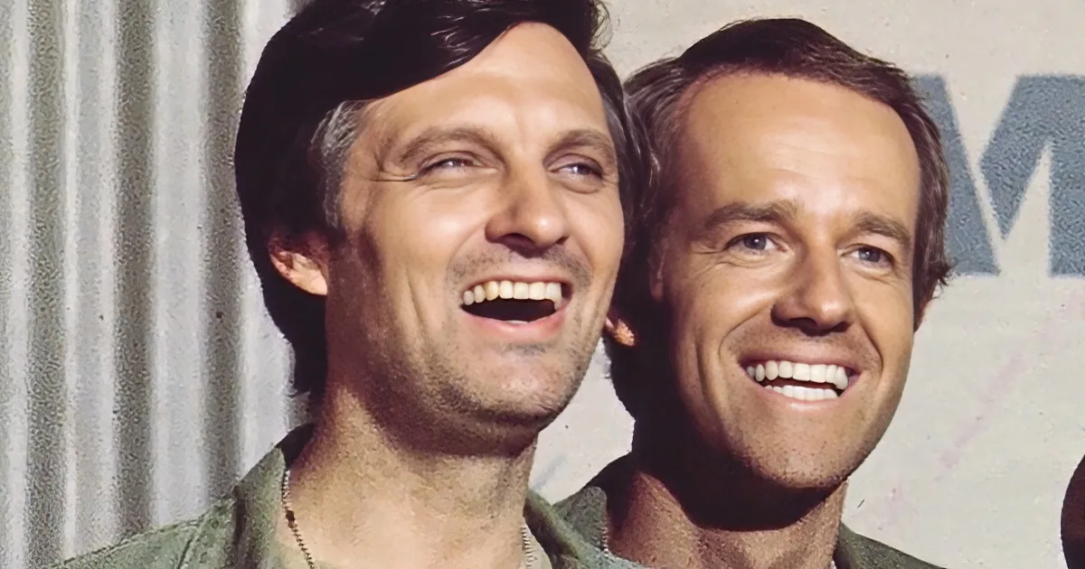 Two men in military attire share a joyful moment, smiling widely.