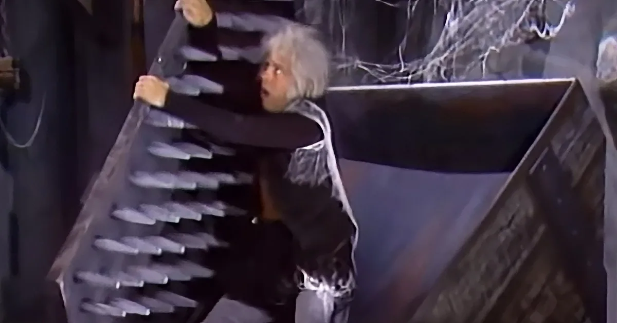 A person with white hair and a black outfit is reaching out towards a wall with sharp protrusions.