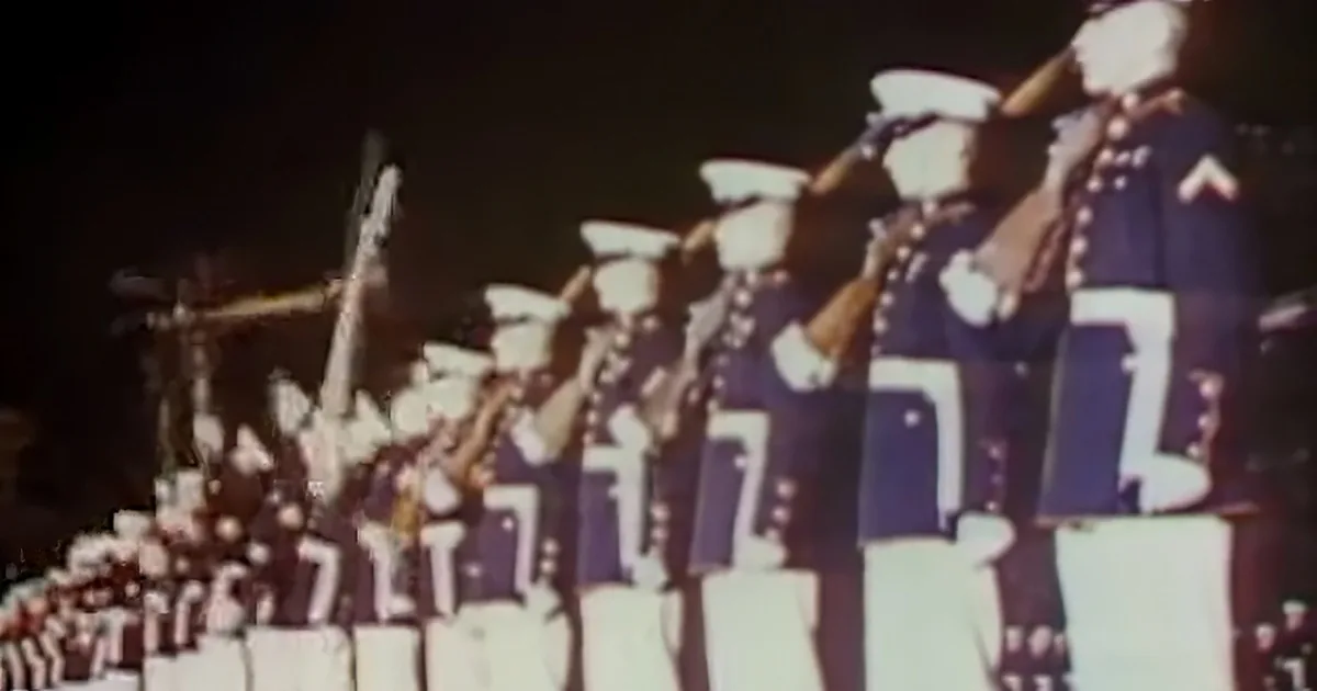 A group of uniformed musicians playing instruments in a nighttime setting.