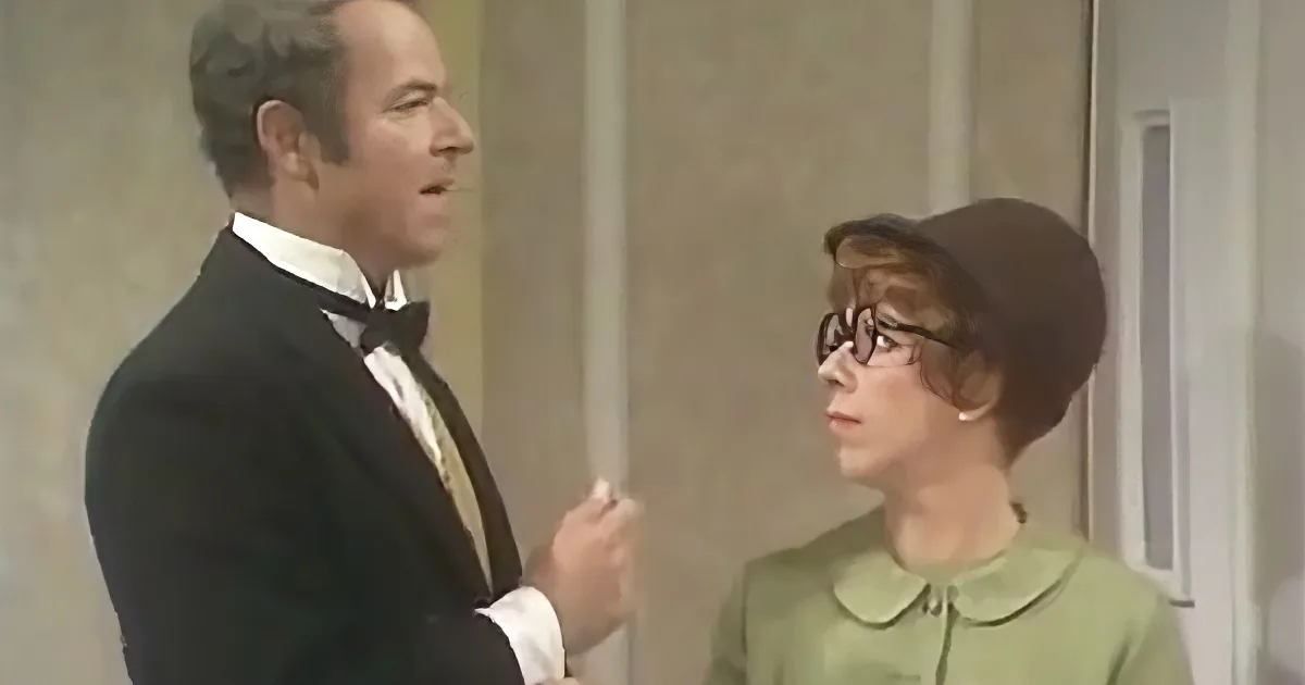 A man in a tuxedo and bow tie is holding a cigarette, standing next to a woman in a green dress and hat.