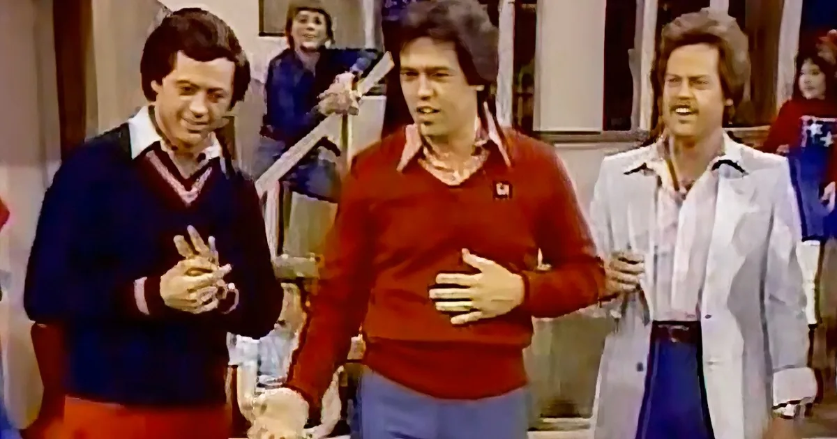 Three men in 70s attire, one in red sweater, another in blue, and the third in white lab coat, appear to be in a comedic...
