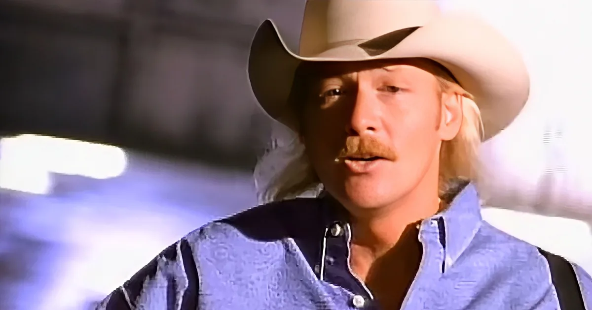 A man in a cowboy hat and denim shirt appears to be speaking or singing.