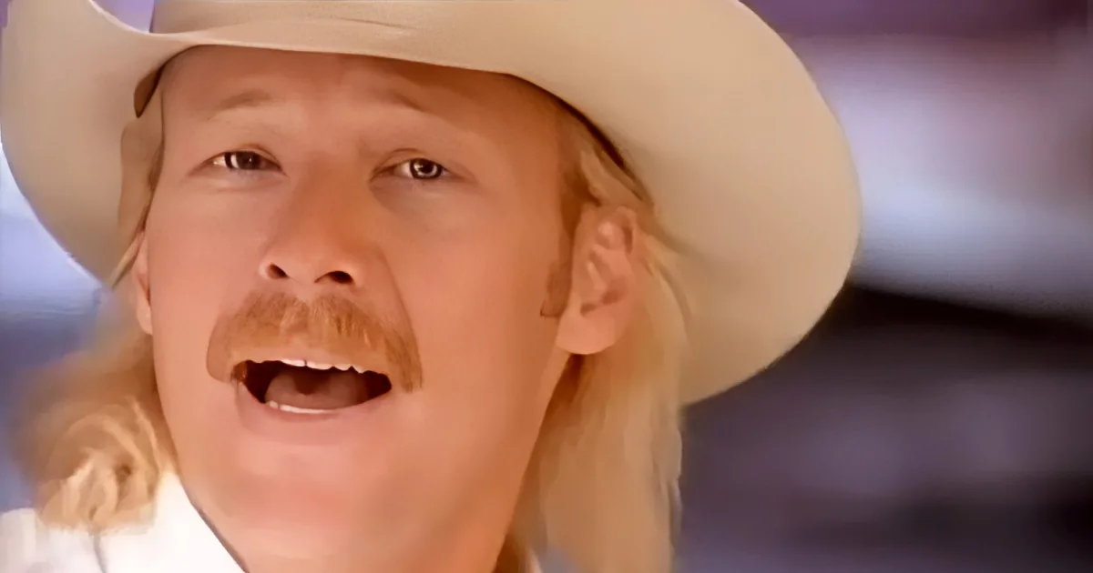 A person wearing a white cowboy hat and a mustache is singing with their mouth open.