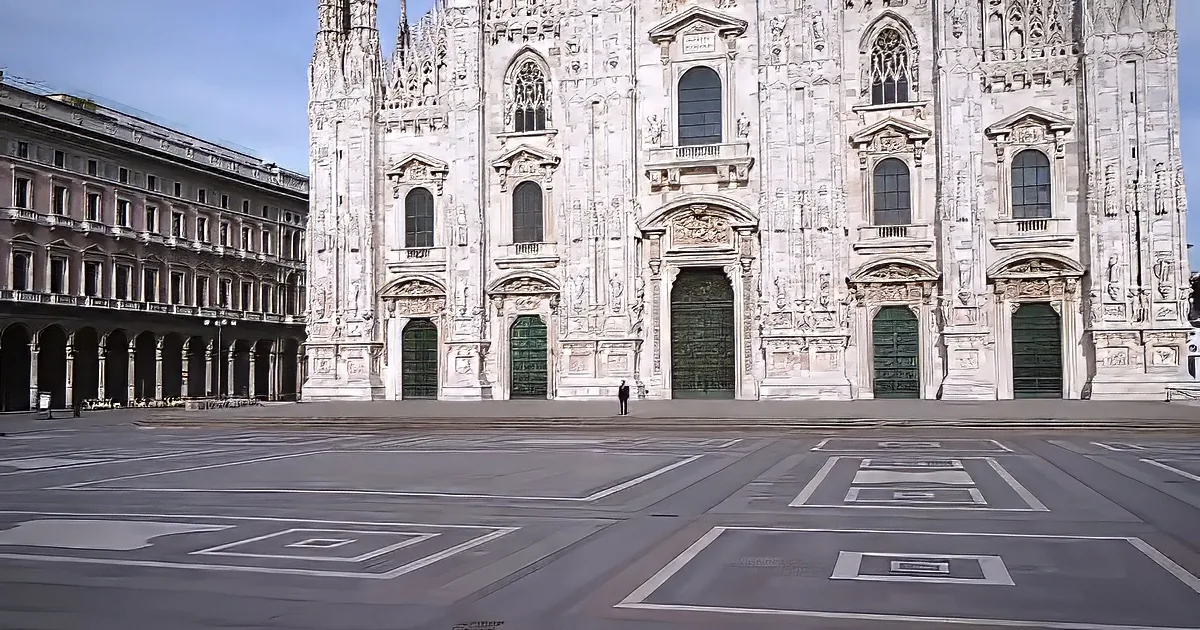 A lone figure stands before the grand facade of the Milan Cathedral on a quiet day.