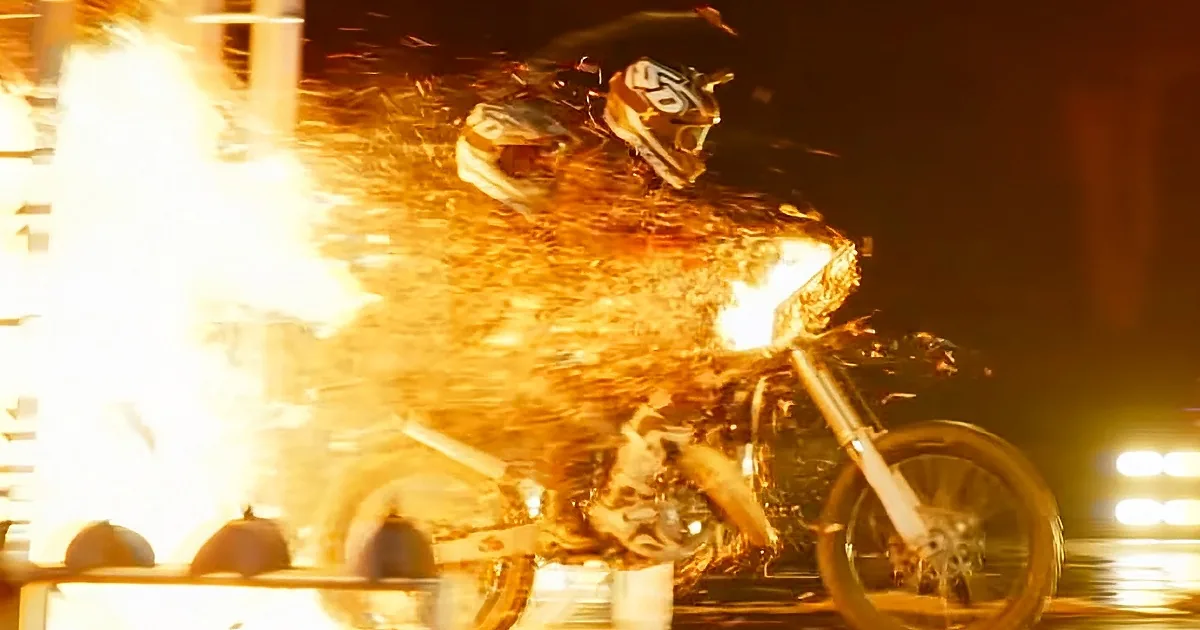 A motorcyclist in a fiery crash, sparks flying, helmet and bike engulfed in flames.