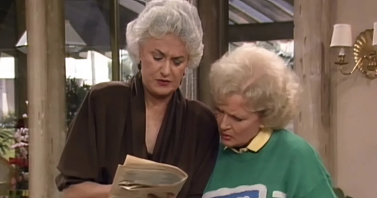 Two women, one reading a book, the other looking concerned, in a cozy indoor setting.