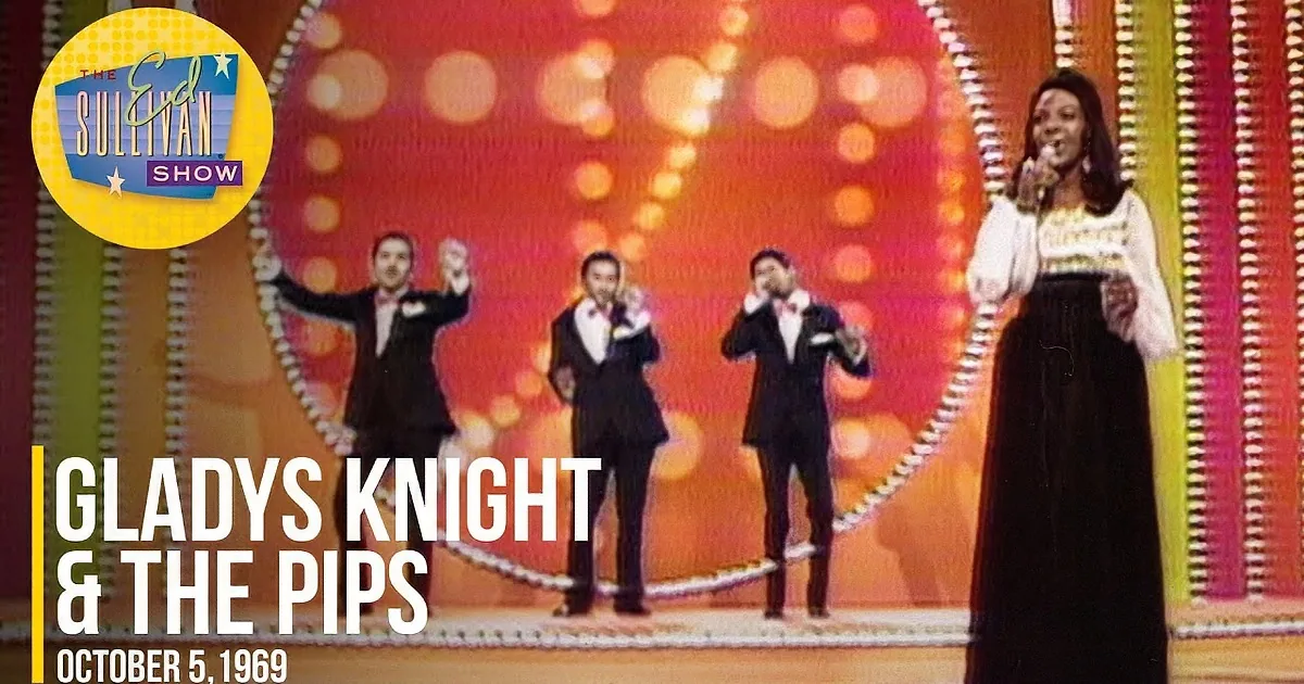 A woman in a white blouse and black skirt sings on stage, accompanied by three men in tuxedos.