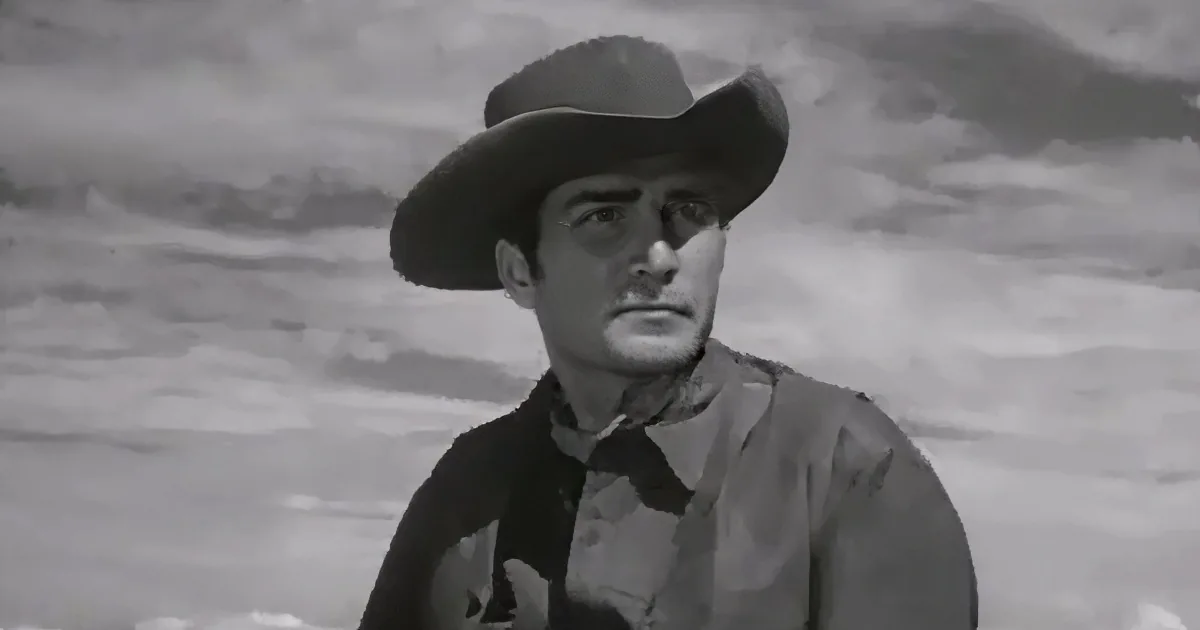 A man in a cowboy hat and shirt stands against a snowy backdrop, looking to the side.