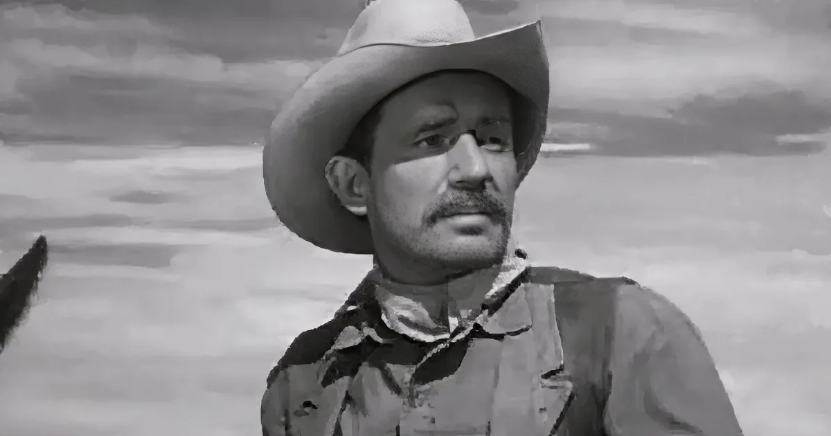 A man in a cowboy hat and vest stands against a cloudy sky, looking to the side.
