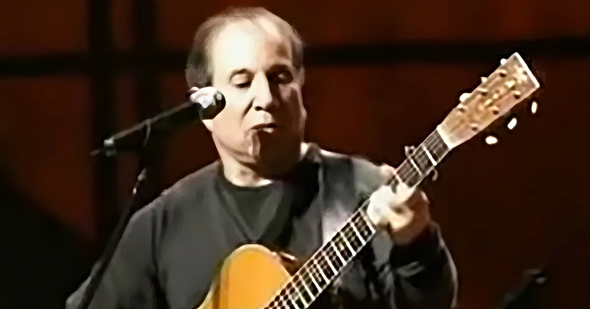 A man plays an acoustic guitar while singing into a microphone.