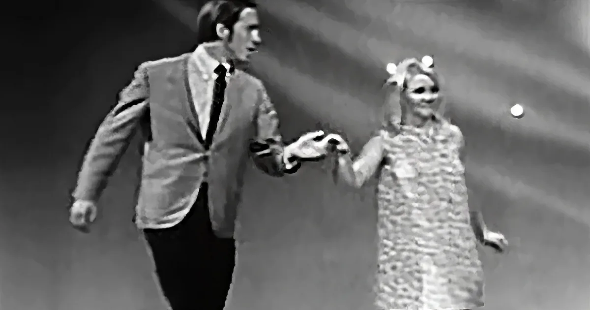 A man in a suit and a woman in a dress are holding hands and walking together.