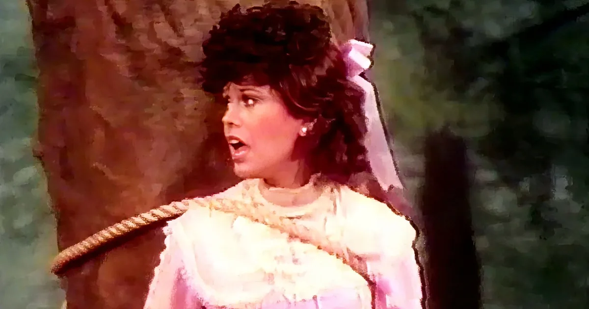 A woman in a white dress with a rope around her neck, looking surprised.