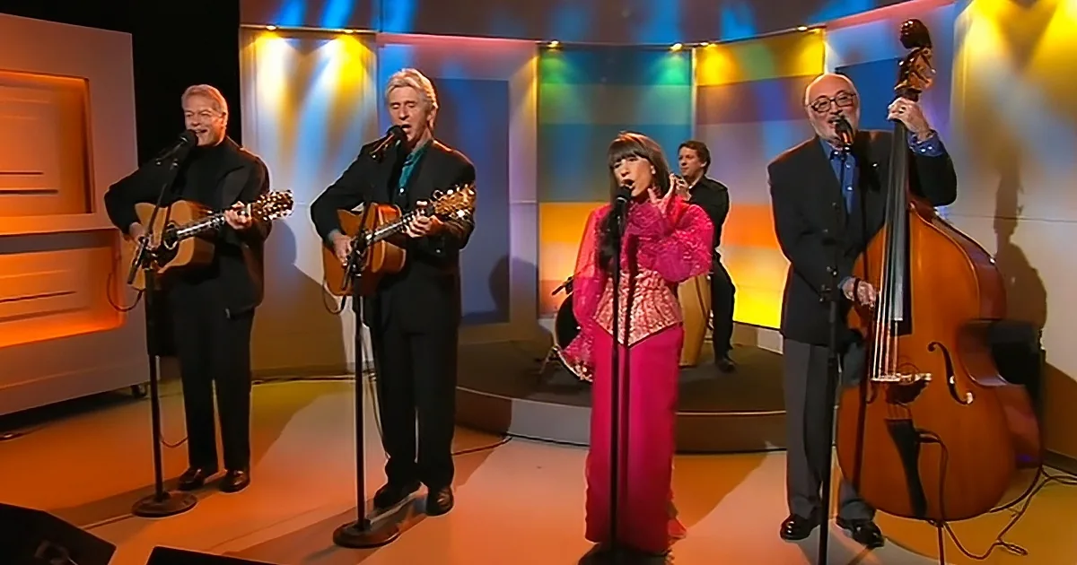 A group of musicians performs on stage with microphones, guitars, and a double bass.