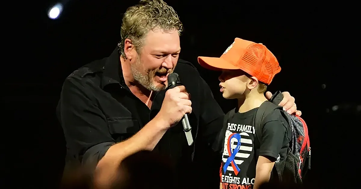 A man and a young boy are on stage, the man holding a microphone, both appear engaged in a performance.