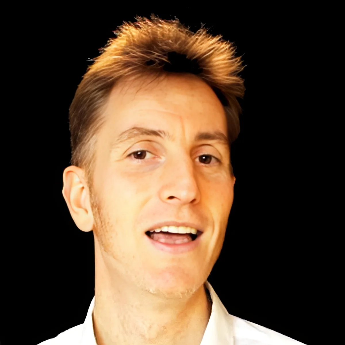 A man with short, spiky blonde hair and a white shirt is smiling.