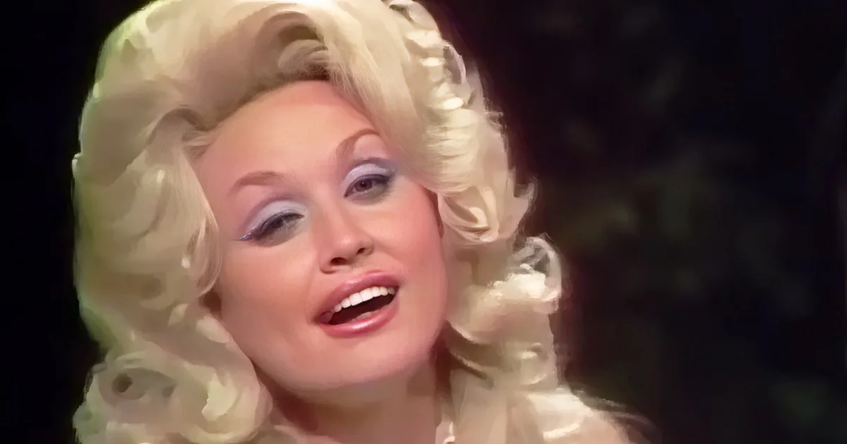 A person with voluminous blonde curls and dramatic makeup is singing.