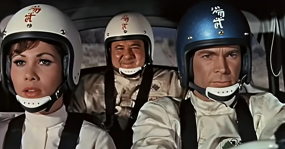 Three individuals in futuristic spacesuits and helmets, strapped in a vehicle, appear to be in a tense situation.