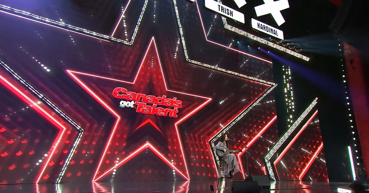 A performer stands on a stage with a large, illuminated "Canada's Got Talent" sign in the background.