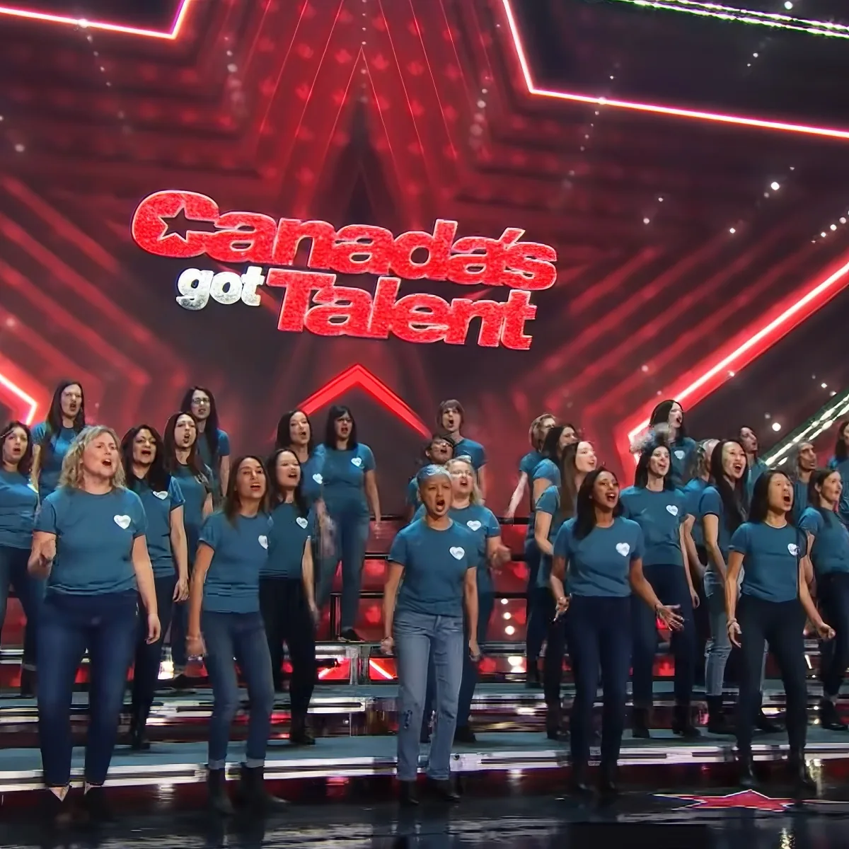 A group of people in blue shirts singing on stage at Canada's Got Talent.
