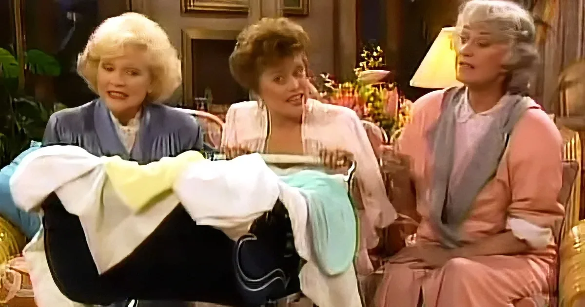 Three women in pajamas are gathered, one holding a baby, in a cozy indoor setting.