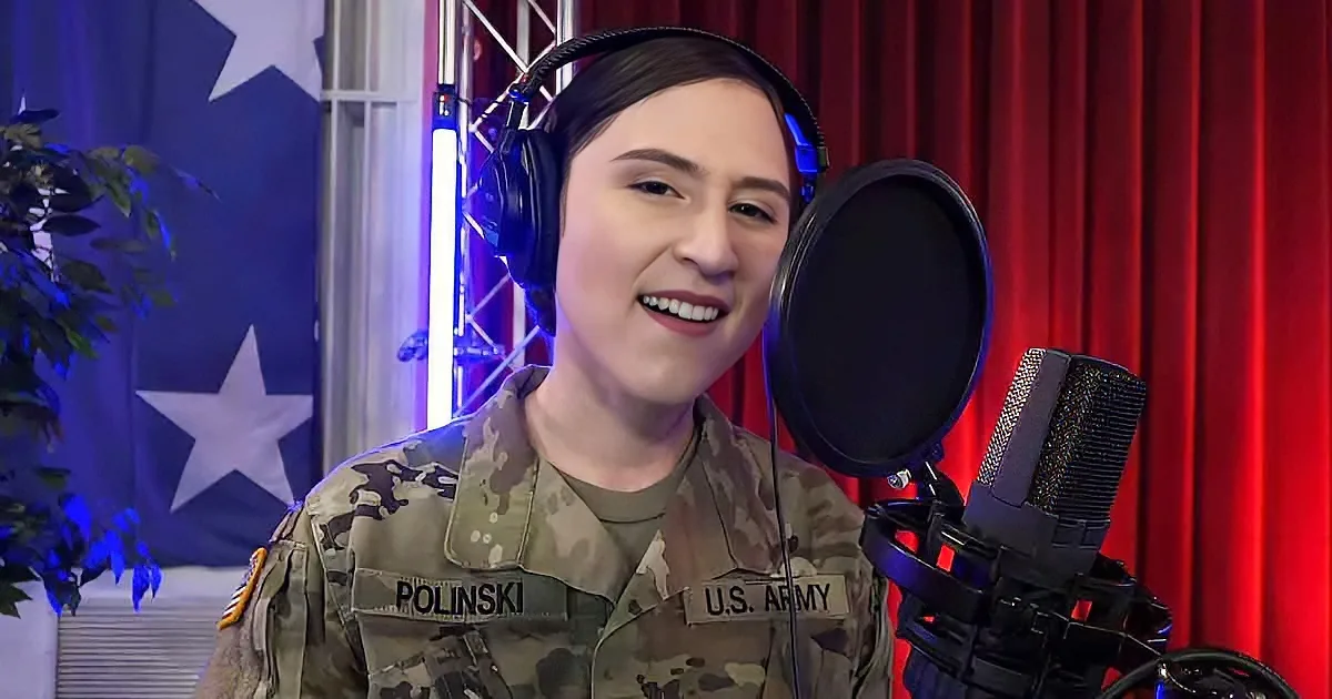 A smiling person in U.S. Army uniform wearing headphones, standing in front of a microphone with a red curtain and a star...