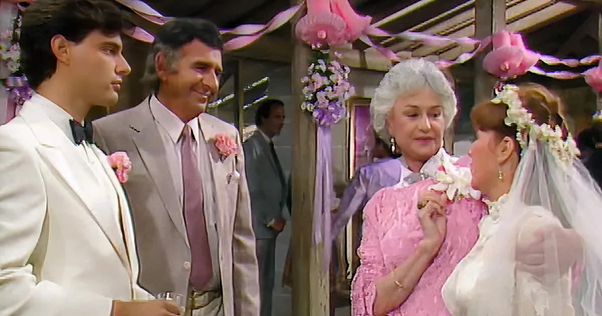 A bride in a pink dress and veil is being comforted by a woman in a purple dress at a wedding.