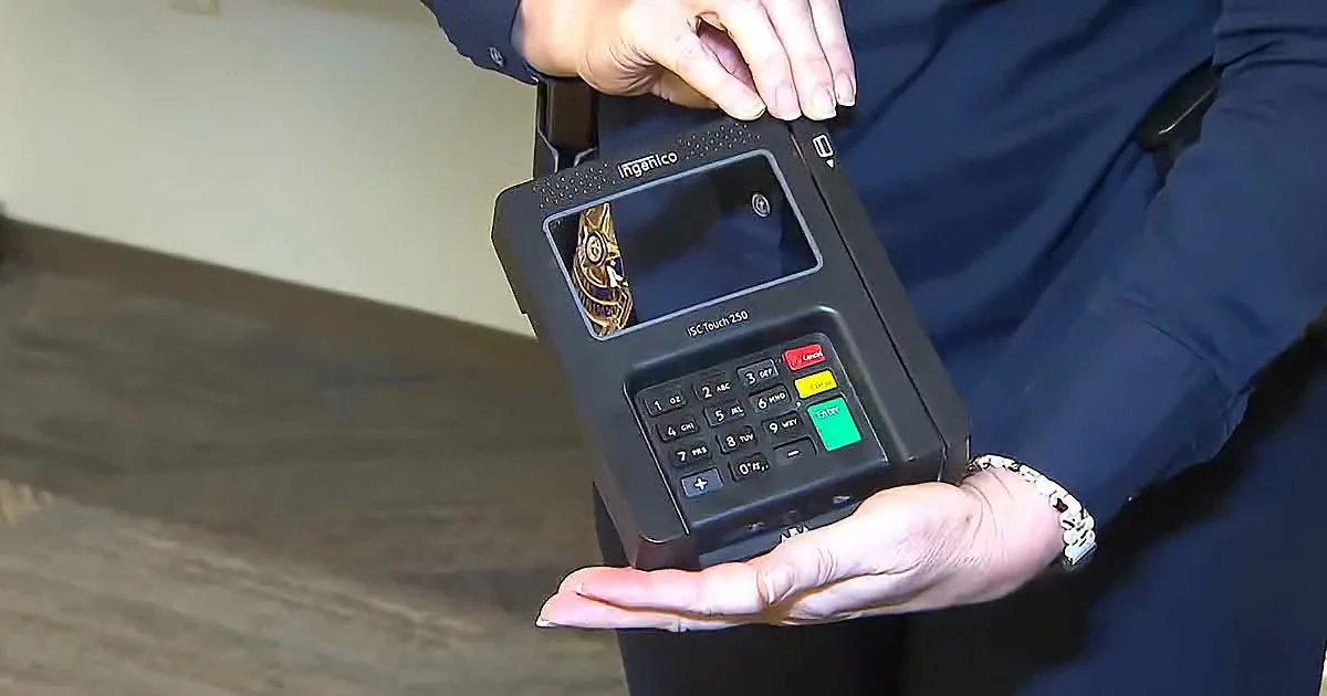 A person holds a black Ingenico ISC Touch 250 payment terminal, displaying a gold emblem on the screen.