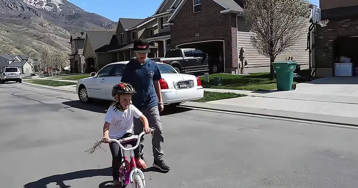 Brother teaches little sister to ride a bike