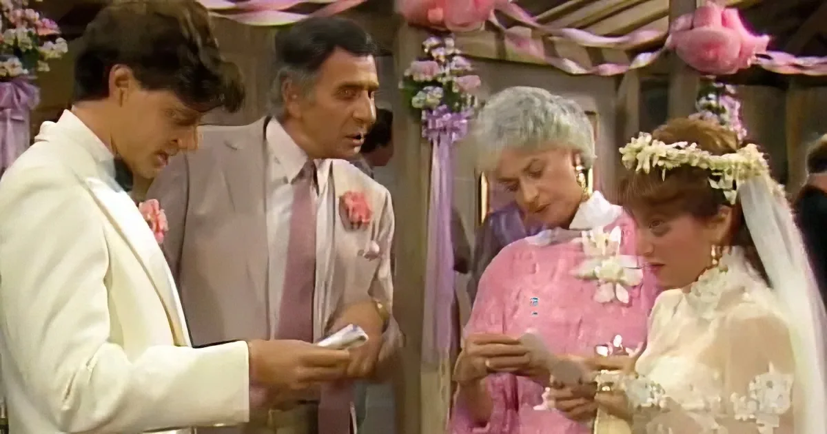 A bride and groom exchange vows during a wedding ceremony, surrounded by family and decorations.