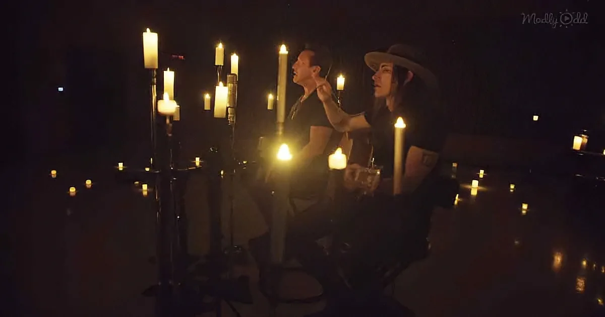 A couple sits in a dimly lit room surrounded by candles, creating a romantic ambiance.